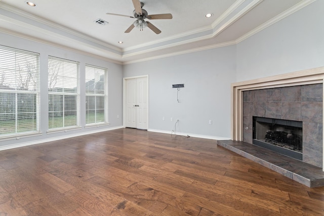 unfurnished living room featuring crown molding, a fireplace, dark hardwood / wood-style flooring, and a tray ceiling