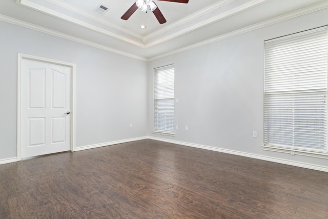 empty room with a raised ceiling, crown molding, dark hardwood / wood-style floors, and ceiling fan