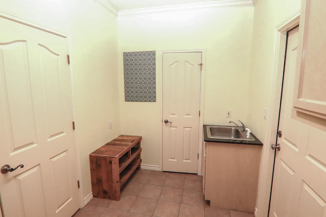 interior space with ornamental molding, sink, and light tile patterned floors