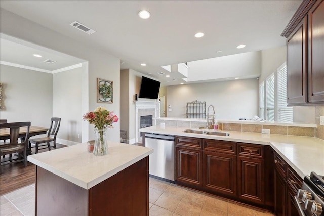 10375 Dominion Ct, Port Arthur, TX 77640 - kitchen featuring appliances with stainless steel finishes, a sink, a fireplace, light countertops, and a peninsula
