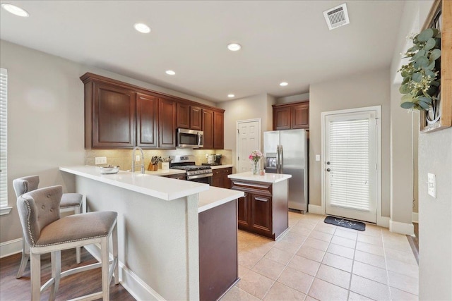 10375 Dominion Ct, Port Arthur, TX 77640 - kitchen with appliances with stainless steel finishes, light countertops, decorative backsplash, a peninsula, and a kitchen breakfast bar