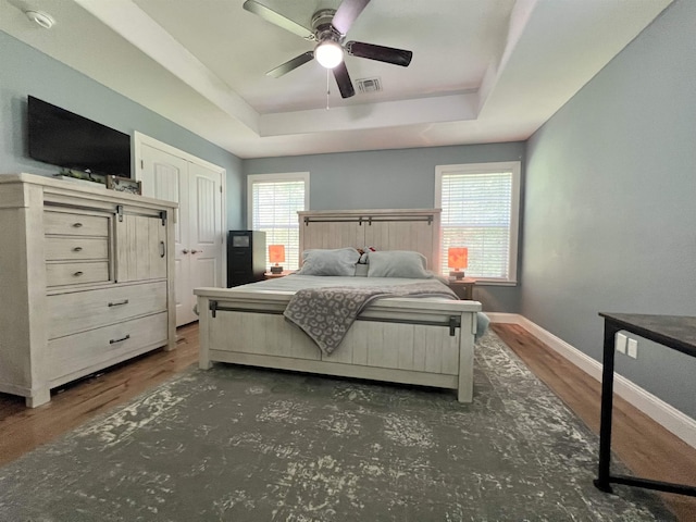 bedroom featuring dark wood-type flooring, a raised ceiling, and ceiling fan