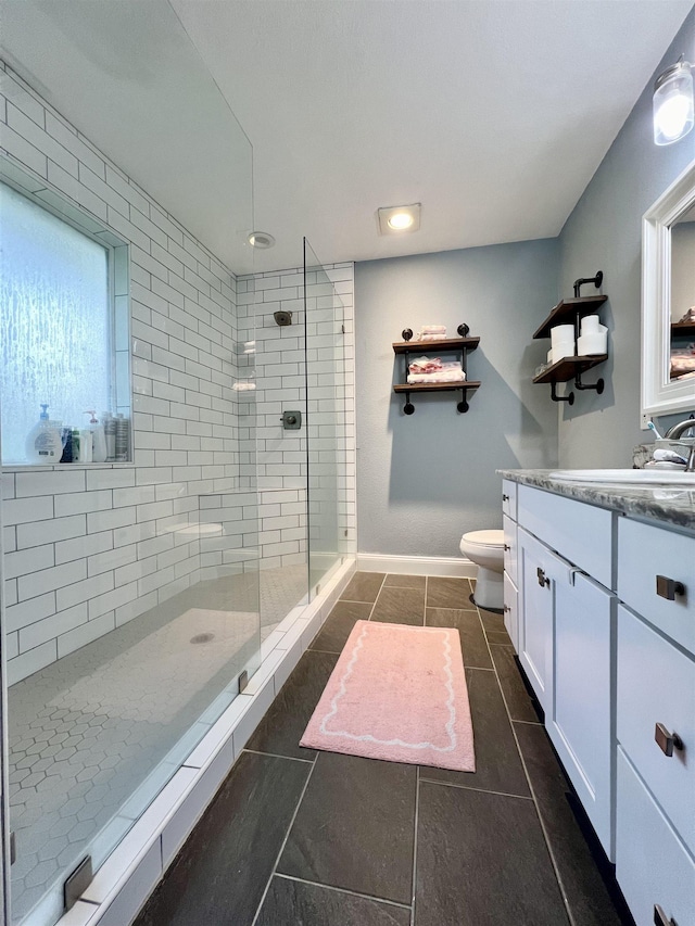 bathroom featuring tile patterned floors, toilet, vanity, and a tile shower