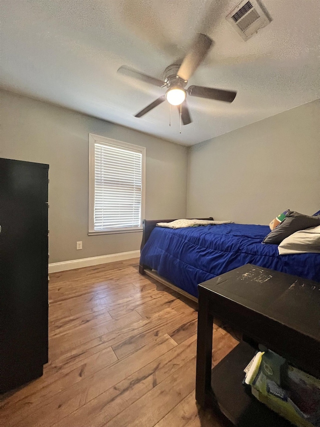 bedroom featuring hardwood / wood-style floors, a textured ceiling, and ceiling fan