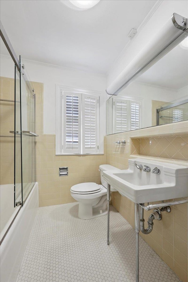 623 20th St, Beaumont, TX 77706 - full bathroom featuring tile walls, toilet, enclosed tub / shower combo, tile patterned floors, and wainscoting