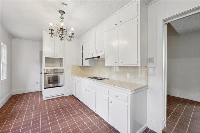 623 20th St, Beaumont, TX 77706 - kitchen with stainless steel oven, a chandelier, white cooktop, under cabinet range hood, and light countertops