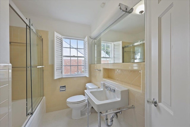 623 20th St, Beaumont, TX 77706 - full bath featuring tile walls, toilet, bath / shower combo with glass door, tile patterned floors, and a sink
