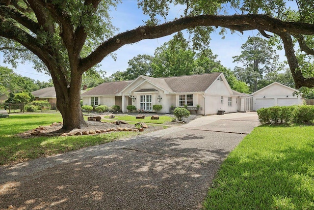 880 Goodhue Rd, Beaumont, TX 77706 - ranch-style home featuring a detached garage, a front lawn, stucco siding, and an outbuilding
