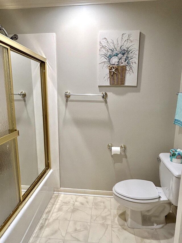 bathroom with toilet and bath / shower combo with glass door