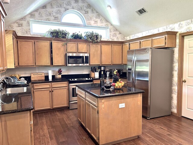 kitchen featuring stainless steel appliances, a kitchen island, dark stone countertops, and sink