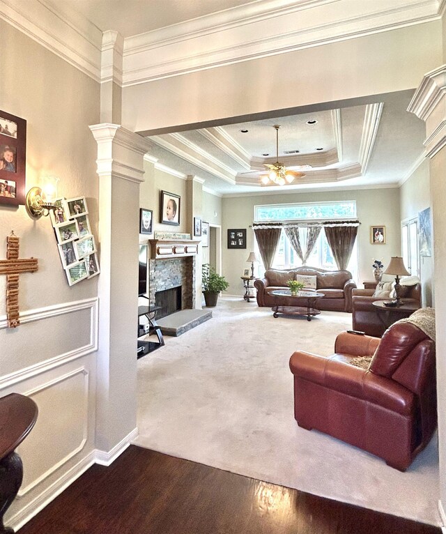 living room featuring a fireplace, ornate columns, crown molding, and a tray ceiling