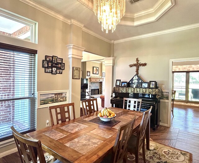 dining space featuring a healthy amount of sunlight, ornate columns, a raised ceiling, and crown molding