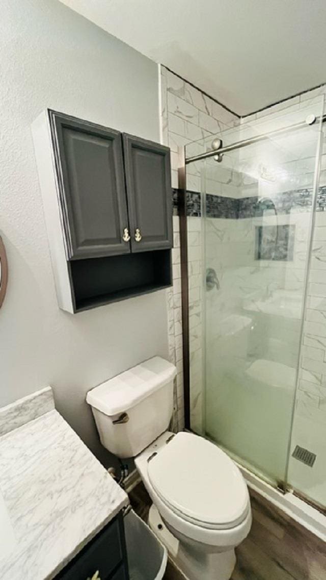 bathroom featuring vanity, toilet, an enclosed shower, and wood-type flooring