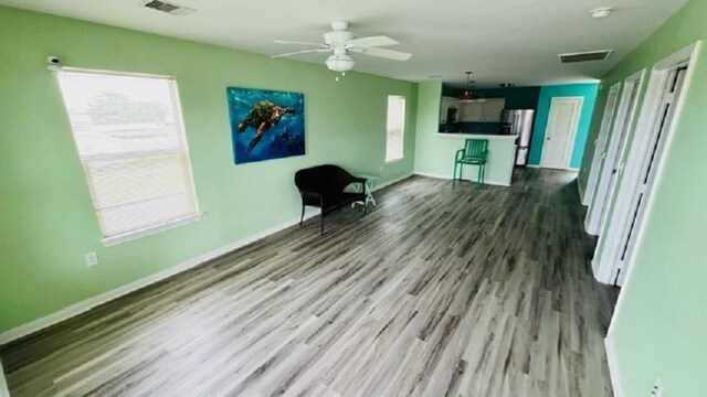 unfurnished living room featuring ceiling fan, plenty of natural light, and dark hardwood / wood-style flooring