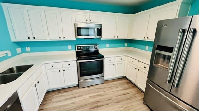 kitchen featuring stainless steel appliances, light hardwood / wood-style floors, sink, and white cabinets