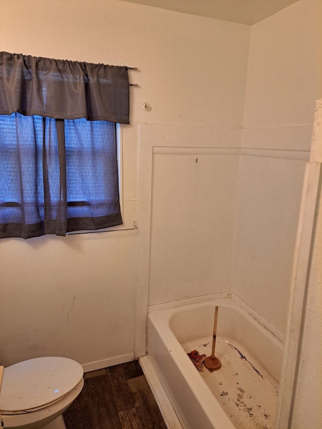 bathroom with hardwood / wood-style flooring, toilet, and a bath