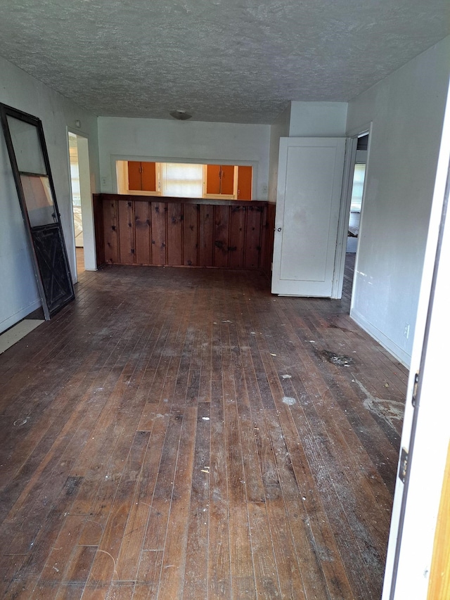 unfurnished living room with a textured ceiling and dark wood-type flooring