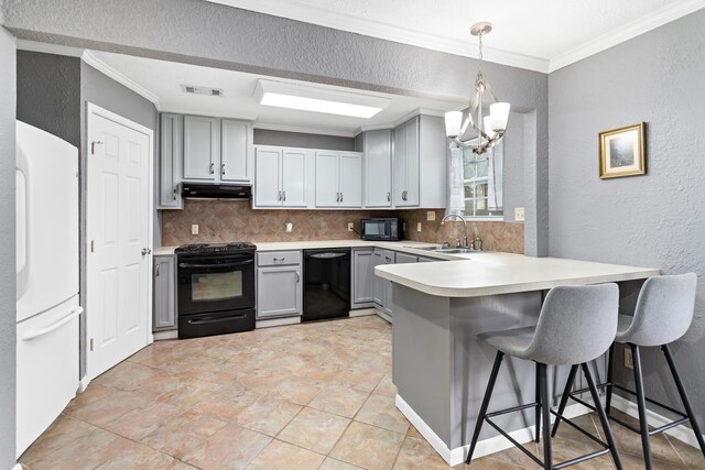 kitchen with pendant lighting, backsplash, gray cabinetry, and black appliances