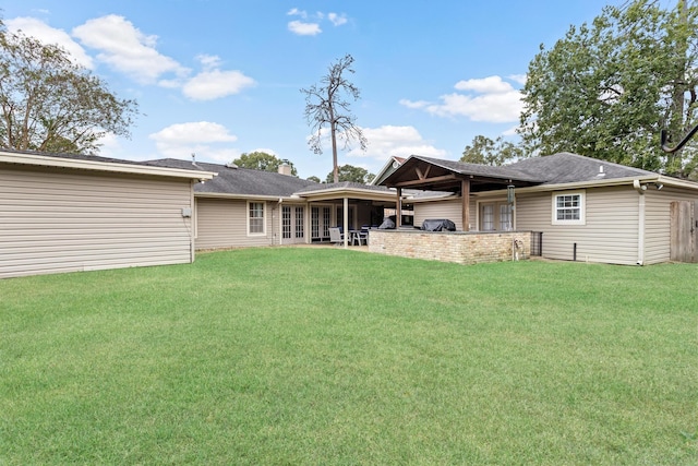 rear view of house featuring a yard, an outdoor kitchen, and a patio