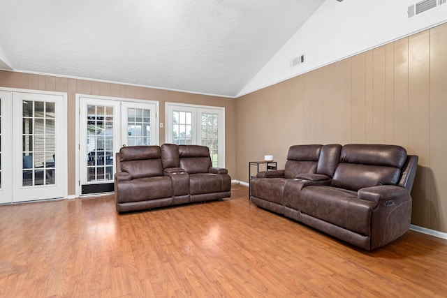 living room with french doors, a textured ceiling, light hardwood / wood-style flooring, and lofted ceiling