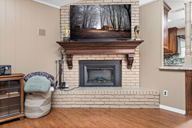 room details with crown molding, wood walls, hardwood / wood-style floors, a textured ceiling, and a fireplace