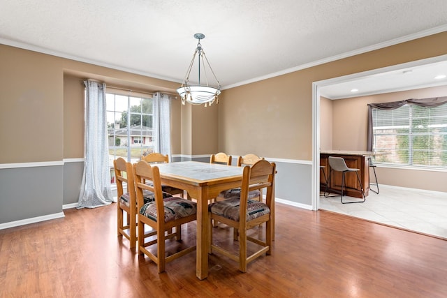 dining area with a textured ceiling, a notable chandelier, crown molding, and light hardwood / wood-style flooring