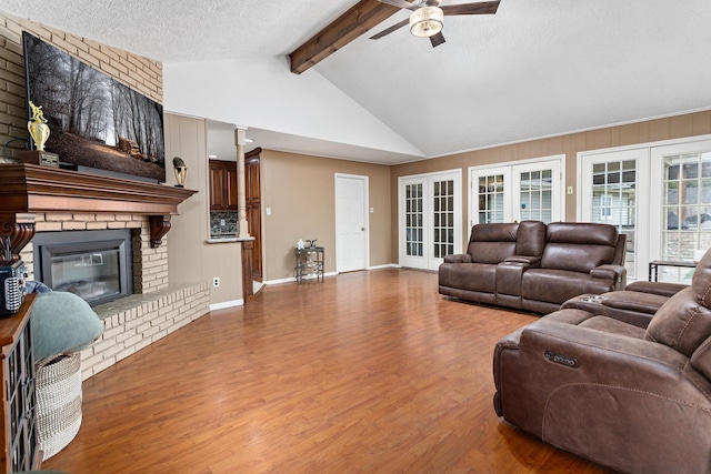 living room featuring ceiling fan, french doors, wood-type flooring, a textured ceiling, and a fireplace