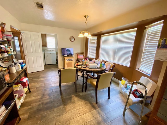 dining area with independent washer and dryer and a notable chandelier