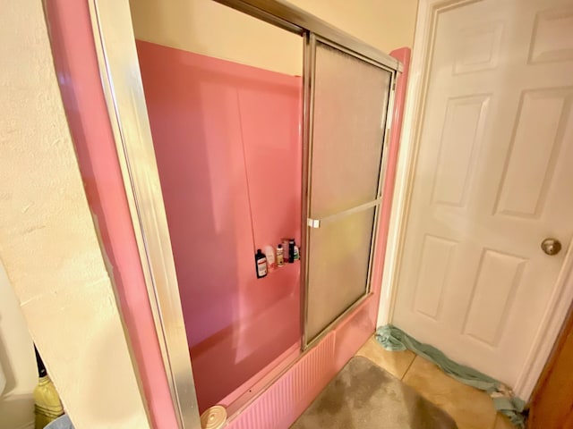 bathroom with tile patterned flooring and combined bath / shower with glass door