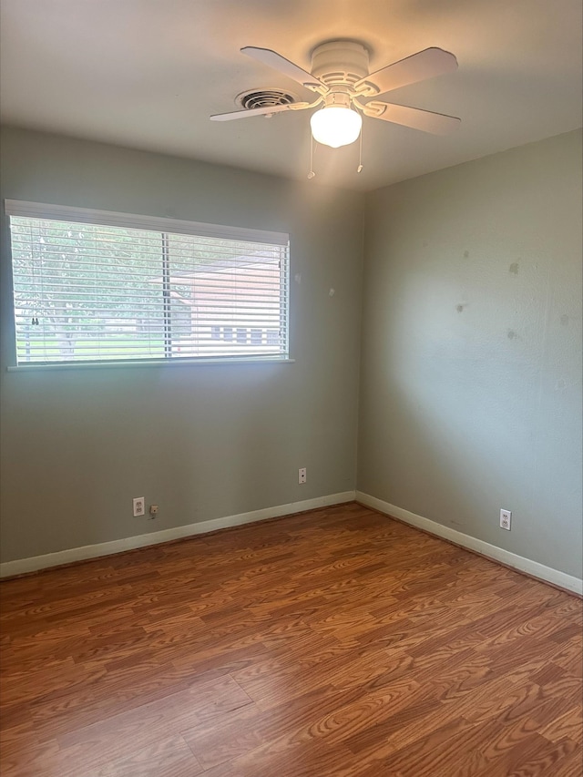 empty room with baseboards, ceiling fan, and wood finished floors