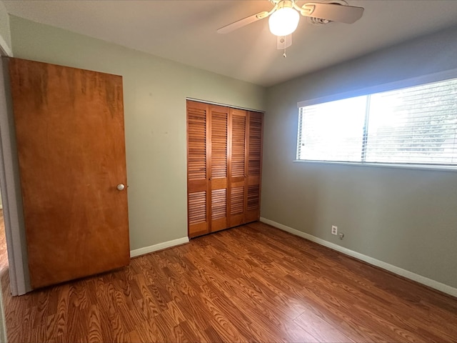 unfurnished bedroom with a ceiling fan, baseboards, wood finished floors, and a closet