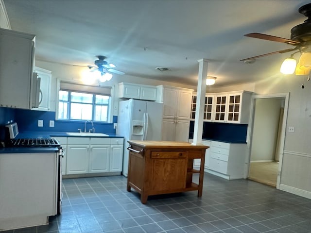 kitchen featuring ceiling fan, a sink, dark tile patterned flooring, white cabinets, and white appliances