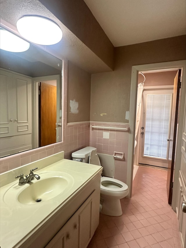 full bath with a shower with curtain, tile walls, vanity, tile patterned floors, and toilet