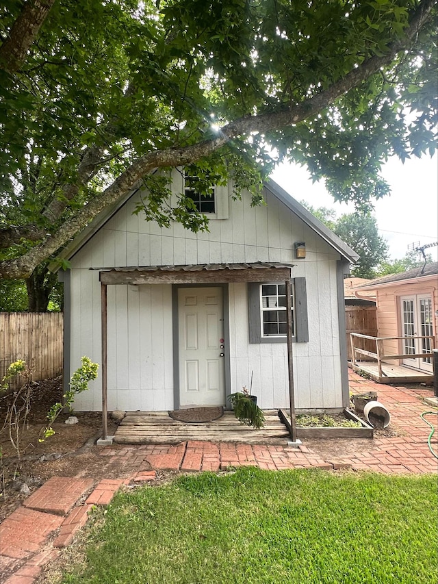 view of outbuilding with fence, an outbuilding, and french doors