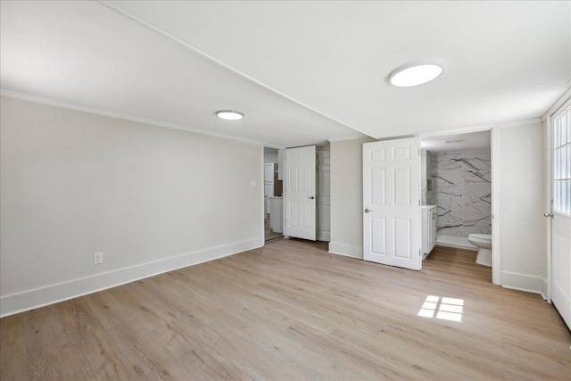 unfurnished bedroom featuring baseboards, wood finished floors, ensuite bath, and ornamental molding