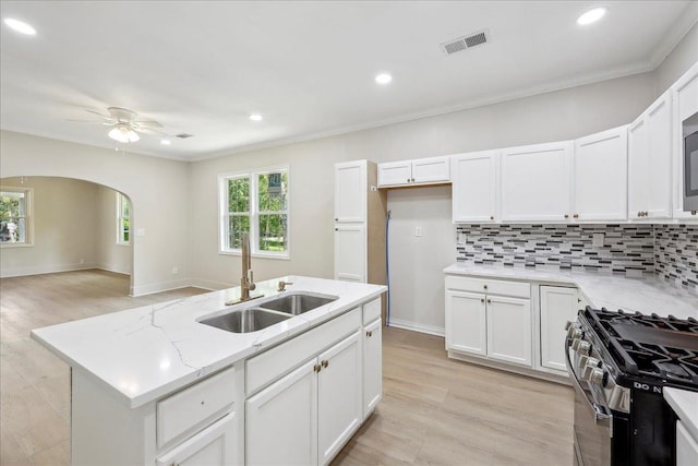 kitchen with a sink, ceiling fan, crown molding, visible vents, and gas stove