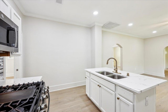 kitchen featuring a sink, stainless steel microwave, visible vents, and arched walkways