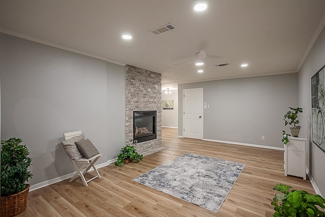 living room with a large fireplace, crown molding, and light hardwood / wood-style flooring