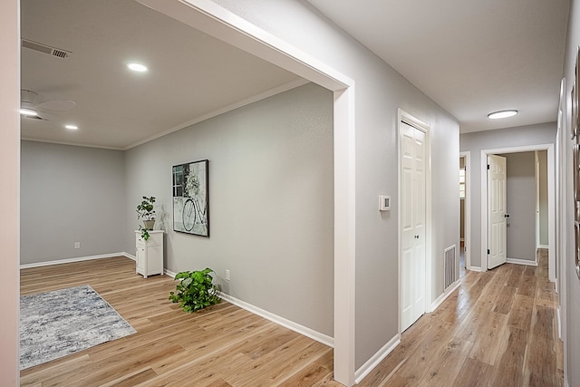 hallway with light hardwood / wood-style floors and ornamental molding