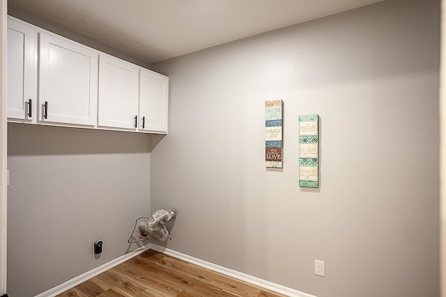 clothes washing area featuring hardwood / wood-style flooring, hookup for an electric dryer, and cabinets