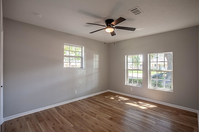 empty room featuring ceiling fan, dark wood-type flooring, and a wealth of natural light