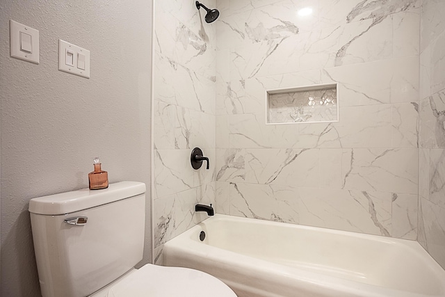 bathroom with tiled shower / bath combo and toilet