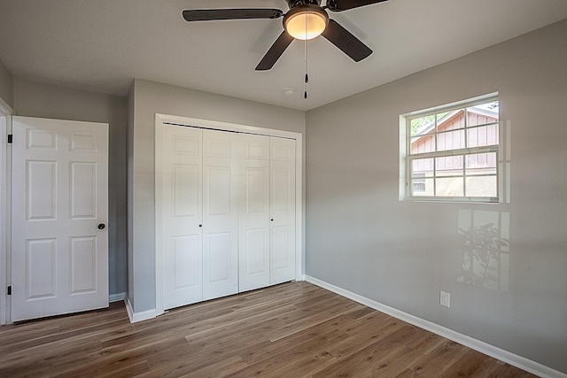 unfurnished bedroom with hardwood / wood-style floors, a closet, and ceiling fan