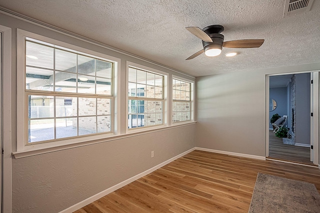 empty room featuring hardwood / wood-style flooring, ceiling fan, and a textured ceiling