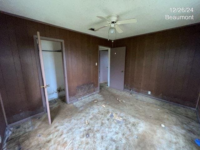 unfurnished bedroom featuring ceiling fan and wood walls