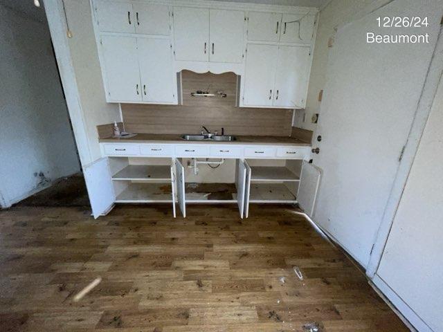 kitchen with dark wood-type flooring, sink, white cabinets, and decorative backsplash