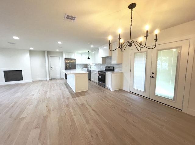 kitchen with a kitchen island, pendant lighting, white cabinets, black appliances, and light wood-type flooring