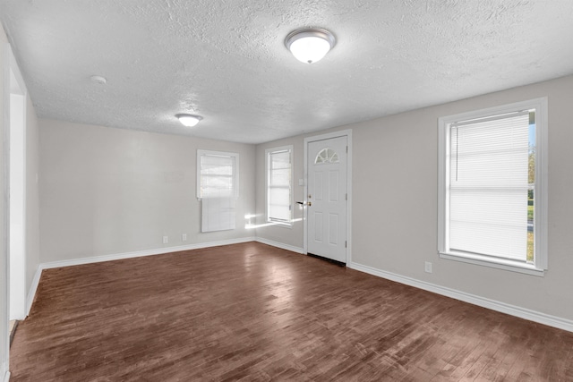 spare room featuring dark hardwood / wood-style flooring and a textured ceiling