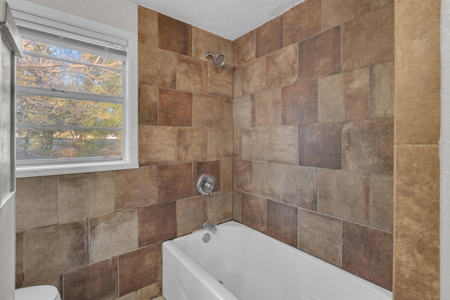 bathroom featuring plenty of natural light, toilet, and tiled shower / bath