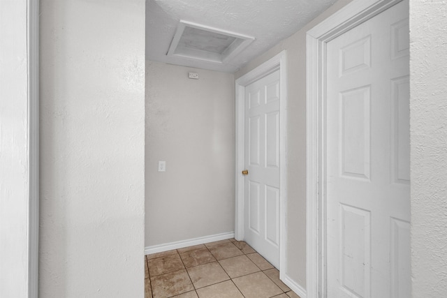 hallway featuring light tile patterned floors and a textured ceiling